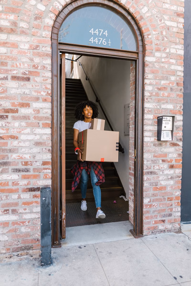 Mover carrying labeled boxes into a sunny Phoenix home